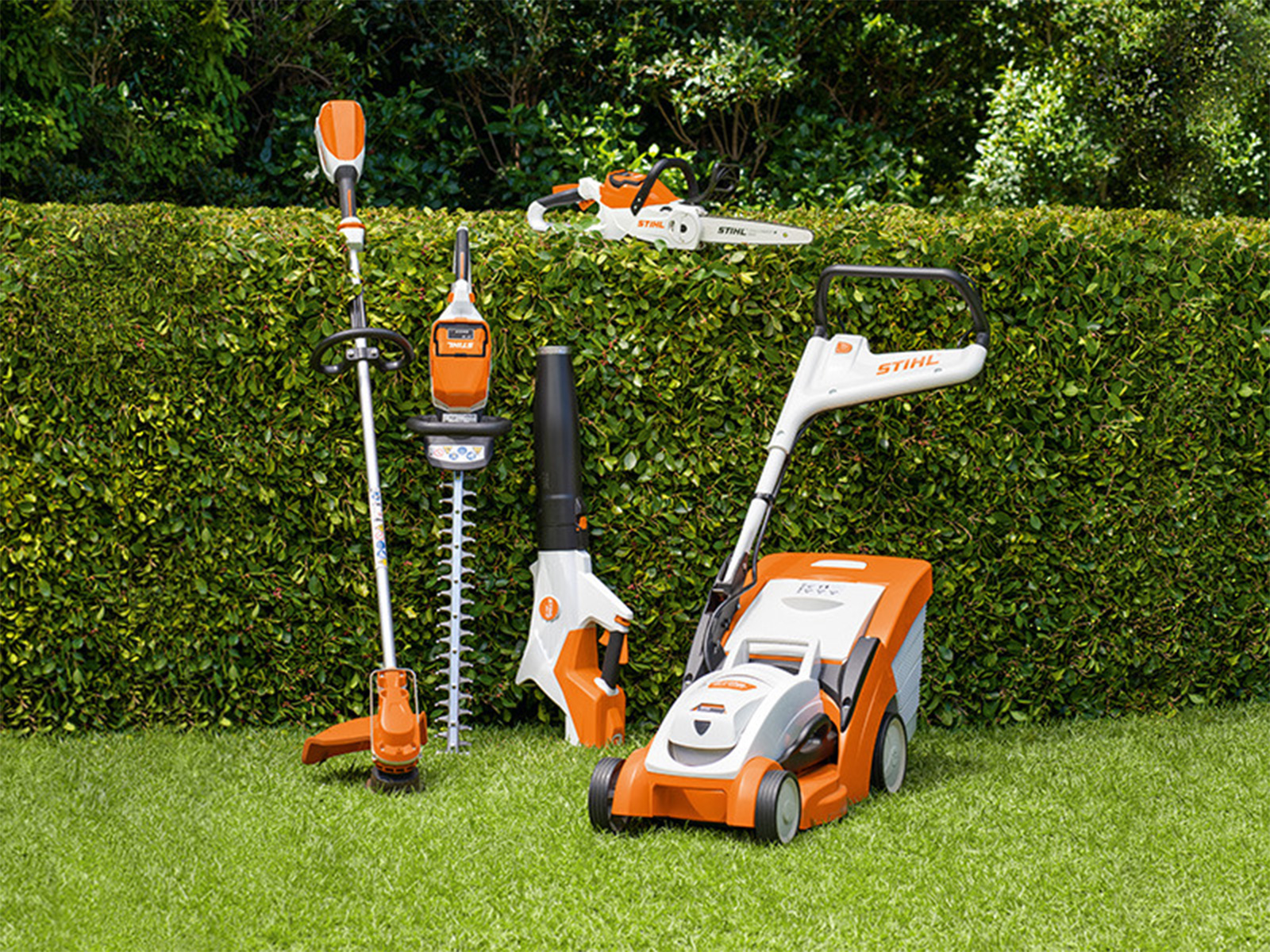 des outils à batterie STIHl dans un jardin contre une haie