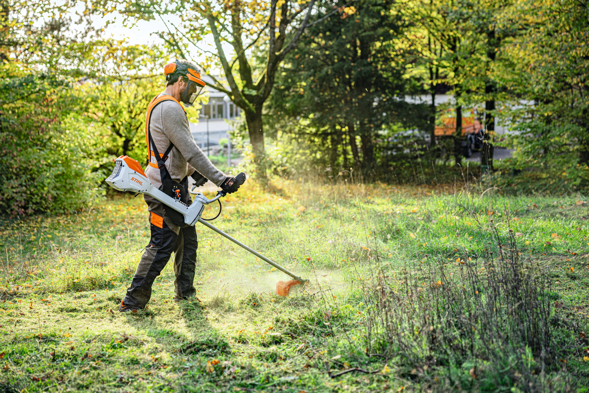 Homme fauchant un espace vert dans un parc avec la débroussailleuse à batterie STIHL FSA 200 